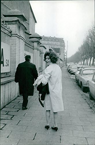 Fotografie de epocă a Irinei Demich mergând pe trotuar, privind înapoi.